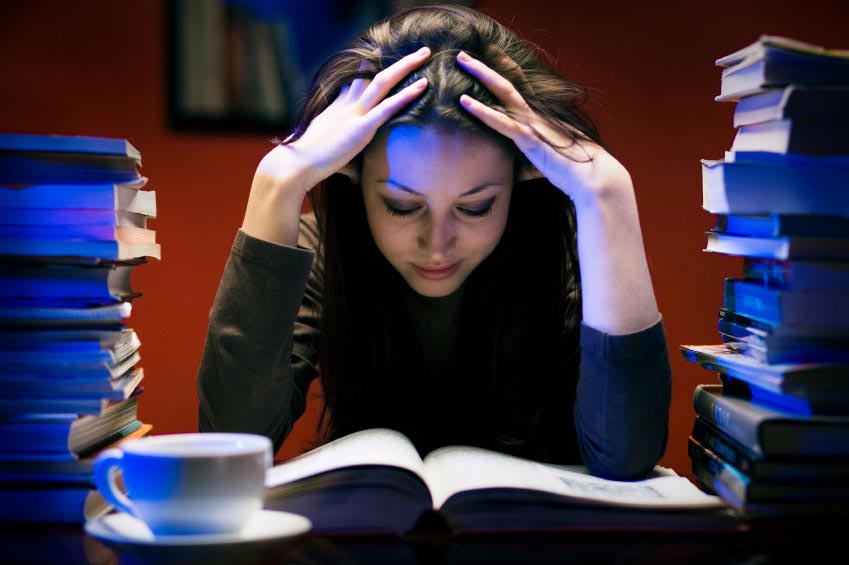 Student in a library surrounded by piles of books